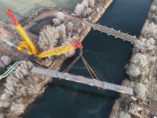 Hier sieht man aus der Luft einen Überblick auf die Gesamtbaustelle und wie der Kran die Brücke hebt.